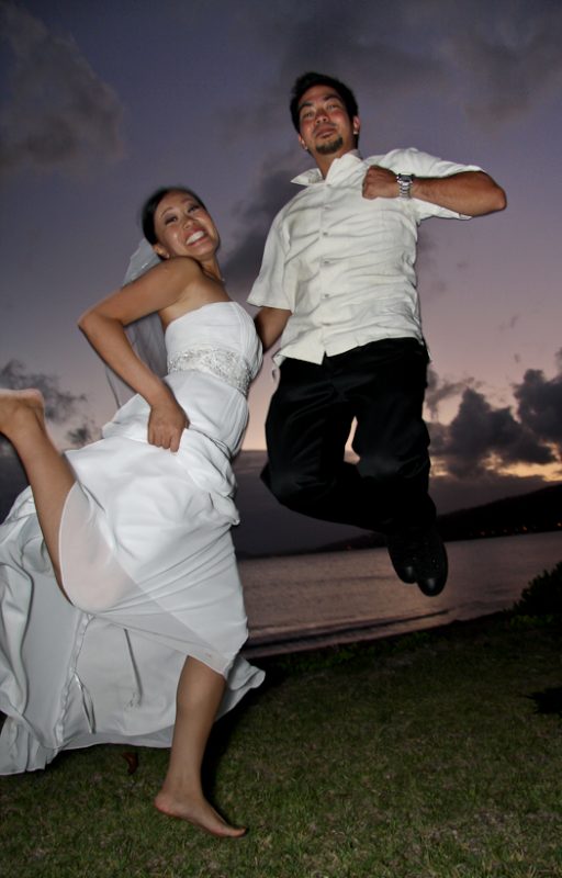 Photo of bride and groom jumping on beach in Hawaii