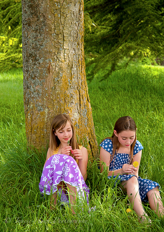 Portrait of two girls sitting by tree in Discovery Park
