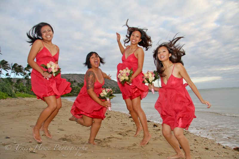 jumping bride's maids in red dresses on a Hawaii beach