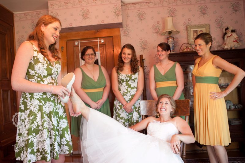 Junior bridesmaid helping bride put on shoes