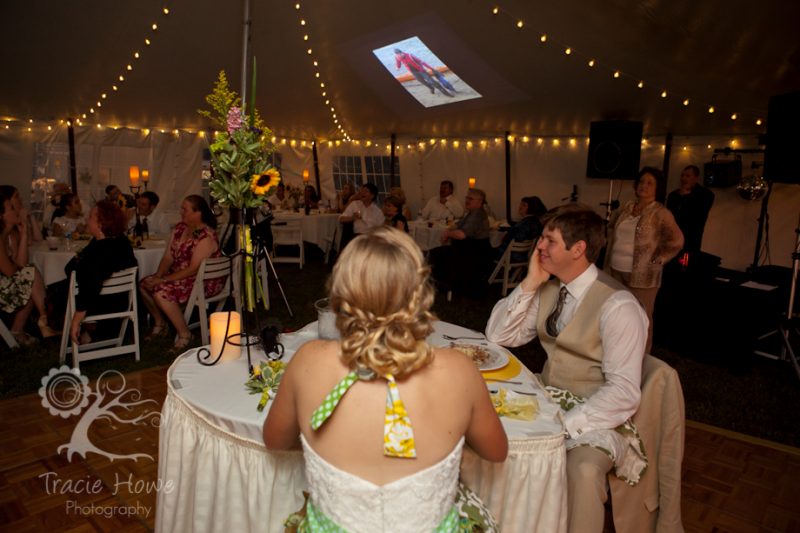 Bride and groom watching slideshow at wedding reception